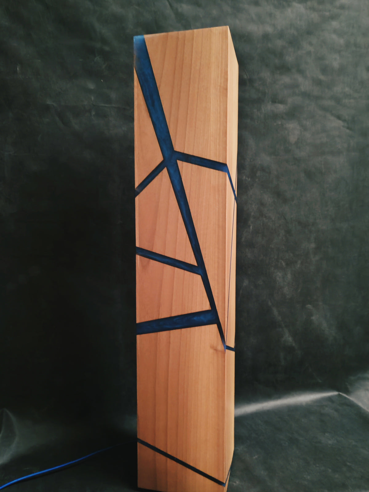 Una lampada da terra dal design slanciato, impreziosita da sottili inserti in resina blu che creano suggestivi giochi di luce