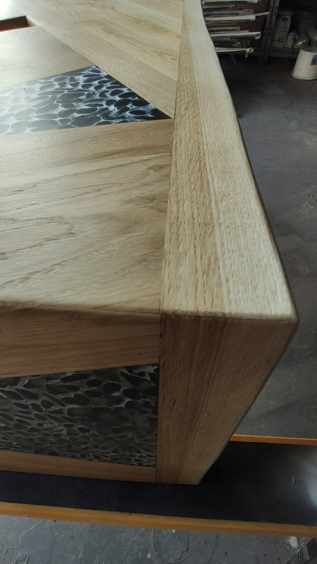 tavolo in quercia, superficie in rovere massello sagomata in pannelli geometrici, con inserti a triangoli di resina traslucida a effetto ciottolato. Linee pulite e volumi decisi definiscono un’estetica contemporanea.